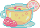 A clear teacup with yellow lemonade, a citrus ring, and rose petals